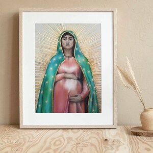 May include: A framed painting of a woman wearing a green and gold robe with a star pattern. She is pregnant and holding her belly. The background is a light gray with gold rays emanating from behind her head.