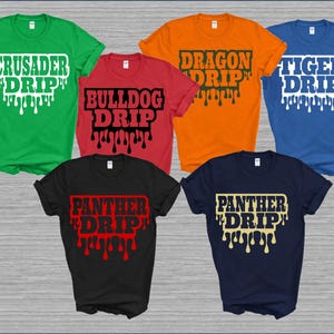 May include: A collection of six short-sleeved t-shirts in various colors, each featuring a unique text design with a dripping effect. The shirts are green, red, orange, blue, black, and navy, with text in contrasting colors.