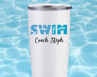以下が含まれることがあります： 白いステンレス製のタンブラーで、青と白のデザインで「SWIM」と書いてあり、各文字に水泳選手のシルエットがあります。「Coach Steph」という文字が「SWIM」の文字の下に書かれています。