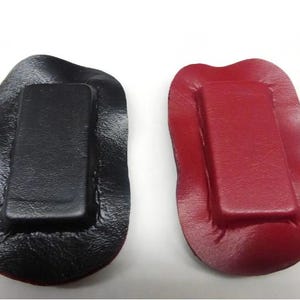 May include: Two rectangular magnets with a black and red leather covering. The magnets are sewn into the leather and have a wavy edge.