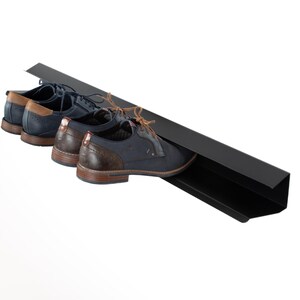 Peut inclure: Un porte-chaussures en m&eacute;tal noir avec trois paires de chaussures en cuir bleu fonc&eacute; avec des accents marrons.