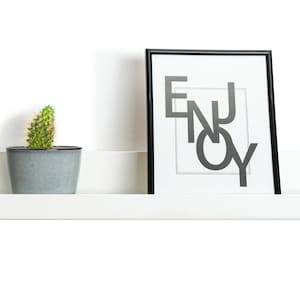 Modern floating metal picture ledge made of 1.5 mm cold-rolled steel, with rounded corners and front lip. Ideal for framed photos, art prints, books, spices or decor. Powder-coated in black, black matt, white, white matt, or brushed stainless steel for industrial, minimalist, or Scandinavian interiors. Wall-mounted with hidden hardware. Available in custom RAL colors and lengths up to 240 cm.