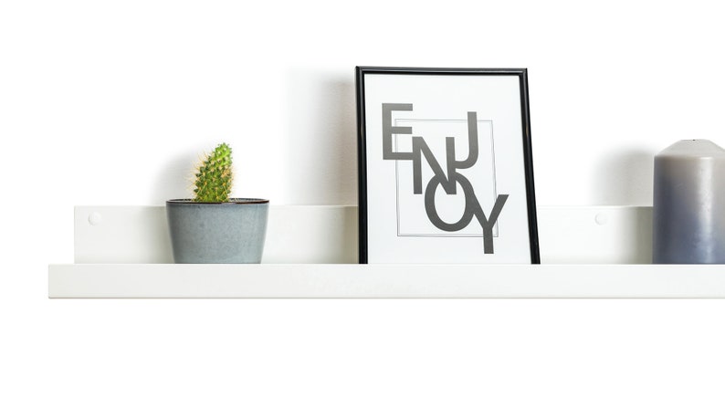 Modern floating metal picture ledge made of 1.5 mm cold-rolled steel, with rounded corners and front lip. Ideal for framed photos, art prints, books, spices or decor. Powder-coated in black, black matt, white, white matt, or brushed stainless steel for industrial, minimalist, or Scandinavian interiors. Wall-mounted with hidden hardware. Available in custom RAL colors and lengths up to 240 cm.