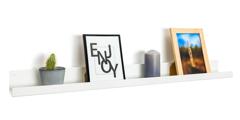 Modern floating metal picture ledge made of 1.5 mm cold-rolled steel, with rounded corners and front lip. Ideal for framed photos, art prints, books, spices or decor. Powder-coated in black, black matt, white, white matt, or brushed stainless steel for industrial, minimalist, or Scandinavian interiors. Wall-mounted with hidden hardware. Available in custom RAL colors and lengths up to 240 cm.