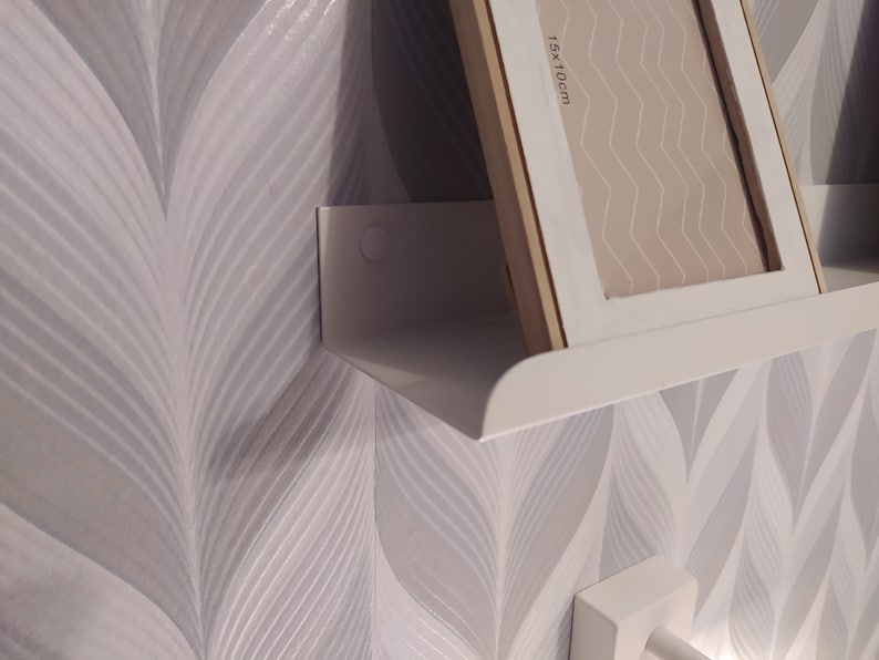May include: White shelf with a white picture frame on top. The frame is labeled "15x10cm".