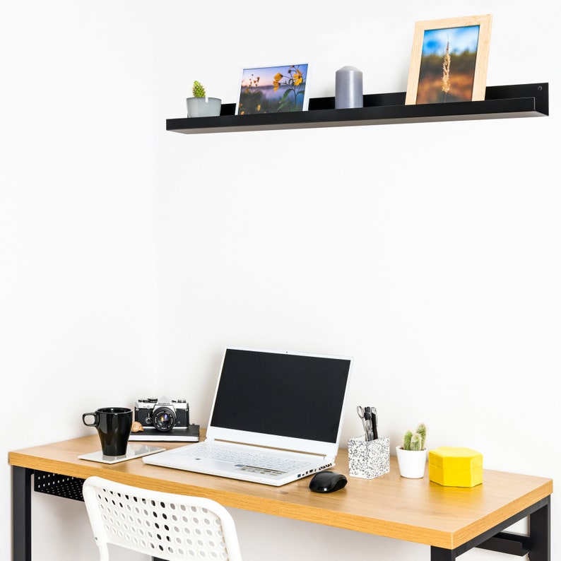 Modern floating metal picture ledge made of 1.5 mm cold-rolled steel, with rounded corners and front lip. Ideal for framed photos, art prints, books, spices or decor. Powder-coated in black, black matt, white, white matt, or brushed stainless steel for industrial, minimalist, or Scandinavian interiors. Wall-mounted with hidden hardware. Available in custom RAL colors and lengths up to 240 cm.