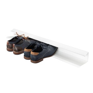 Peut inclure: Un porte-chaussures blanc avec deux paires de chaussures, une paire est noire et l'autre est marron.