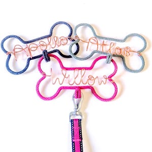 May include: Three dog leash holders in the shape of a bone. The bone is made of rope and has a metal wire name on it. .