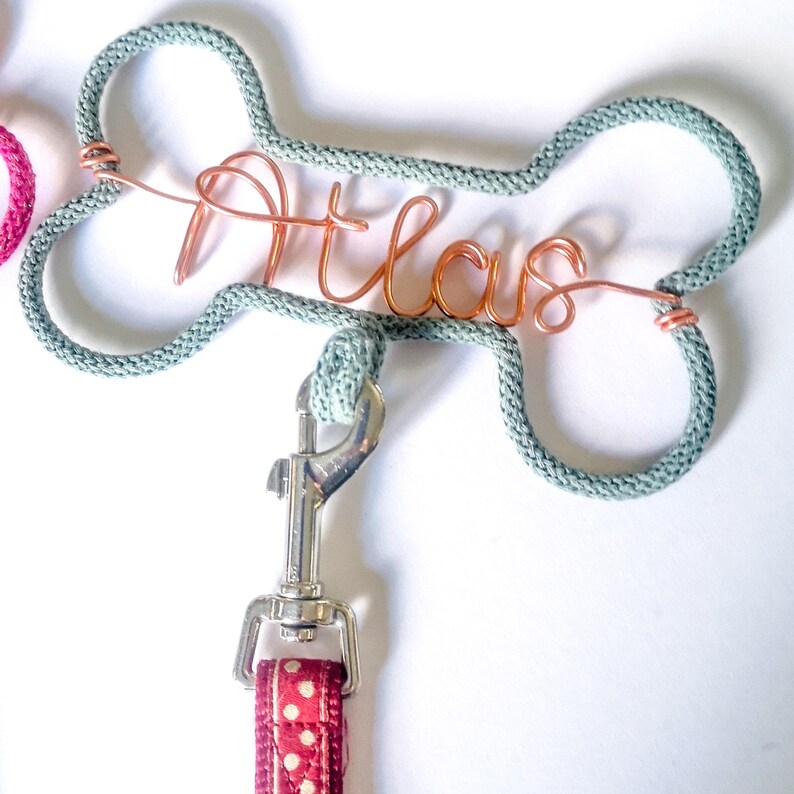 close up of A grey marl dog leash hook,  with a the name Atlas in copper wire.