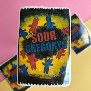 Peut inclure: Un autocollant avec un fond noir et une bordure jaune. L'autocollant présente une image de dessin animé d'un sac de bonbons avec le texte "Not Sour Gregorys" et la phrase "Nothing Sus Here".