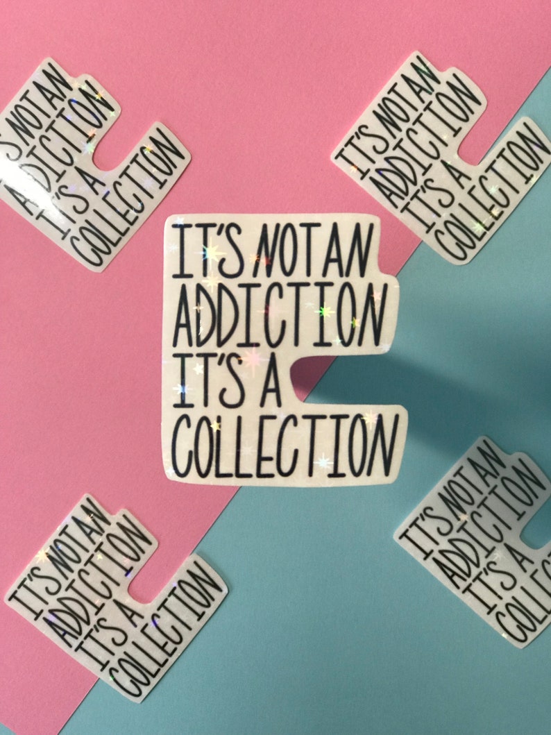 May include: White stickers with the text "IT'S NOT AN ADDICTION IT'S A COLLECTION" in black. The stickers have a holographic, glittery effect. The background is divided diagonally into pink and blue sections.