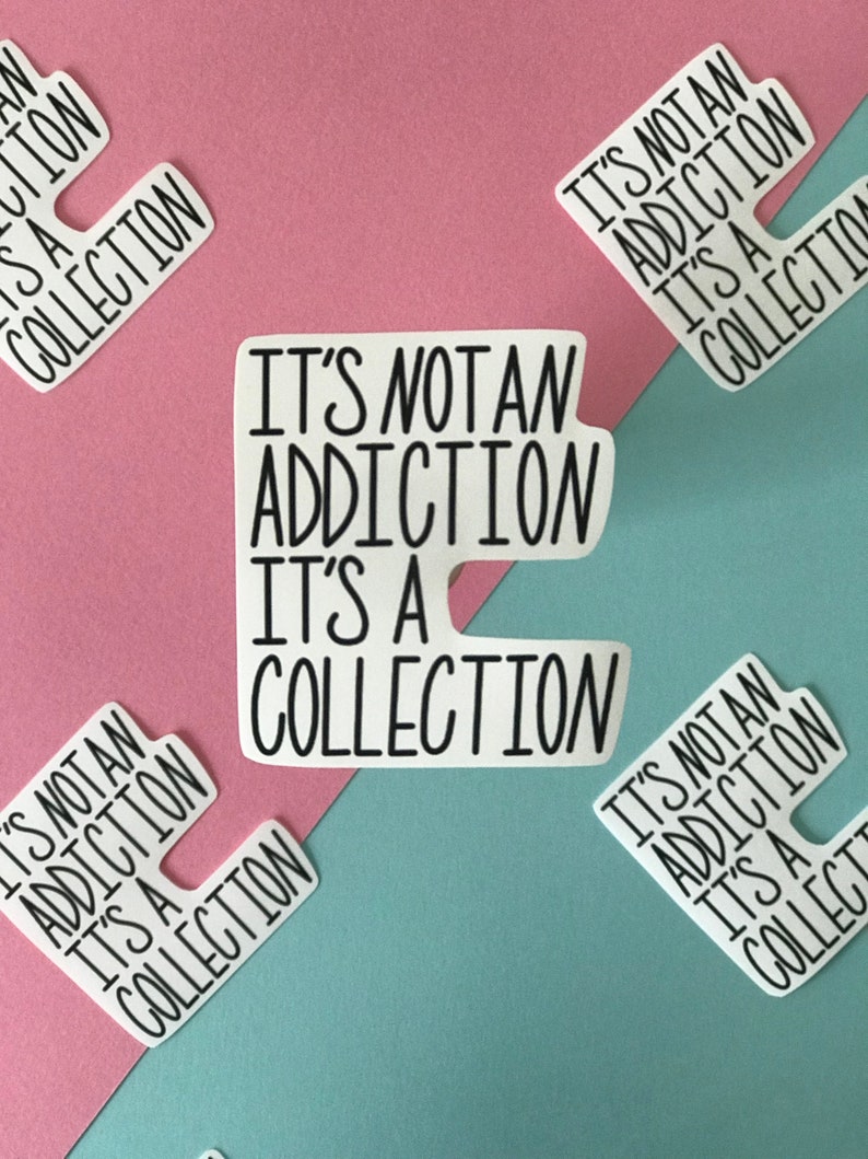 May include: White stickers with the text "IT'S NOT AN ADDICTION IT'S A COLLECTION" in black, arranged on a pink and teal background. The stickers are in a unique shape, with a cutout on one side.