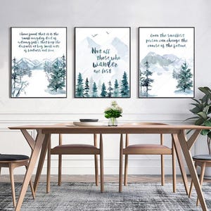 May include: Three framed watercolor prints with mountain and forest scenes. Each print has a different inspirational quote in black text. The color palette includes shades of blue, green, and white, creating a serene and natural aesthetic.