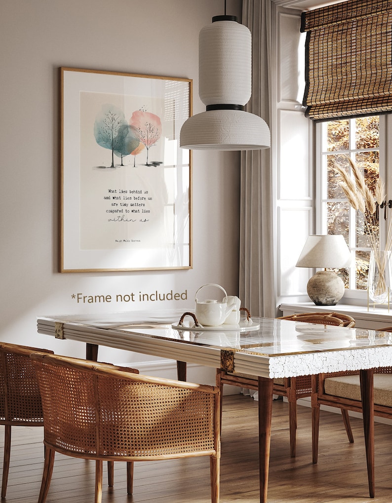 May include: A watercolor print with a quote about what lies behind us and what lies before us. The print is framed and hanging on a wall in a dining room with a white table and chairs.