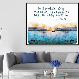 May include: Watercolor art print in a black frame. The artwork depicts a seascape with mountains, a whale, and the text "in trouble, deep trouble, I prayed to God. He answered me. Jonah 2:2." The color palette includes blues, yellows, and greens.