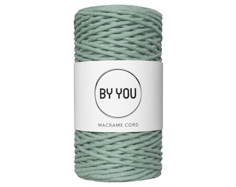Pode incluir: Um rolo de cordão de macramé verde-sálvia com um rótulo branco que diz "BY YOU MACRAME CORD".