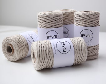 May include: Four spools of natural colored macrame cord with white labels that say "BY YOU" and "MACRAME CORD".