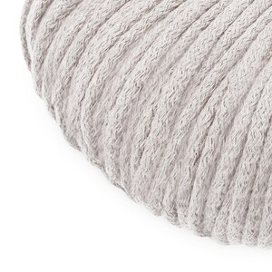 May include: A round, light grey, plush cushion with a ribbed texture.