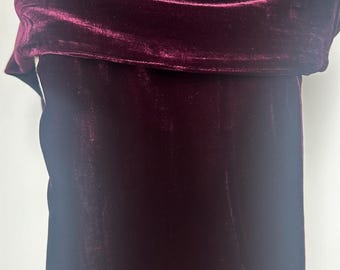 May include: A deep burgundy velvet garment, possibly a top or dress, displayed on a mannequin. The fabric has a soft sheen and is gathered at the neckline, creating a draped effect. The rich color and texture suggest a formal or evening wear item.