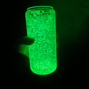 May include: A clear glass tumbler with a green glow and white glitter inside. The tumbler is lit from within, creating a bright green light.