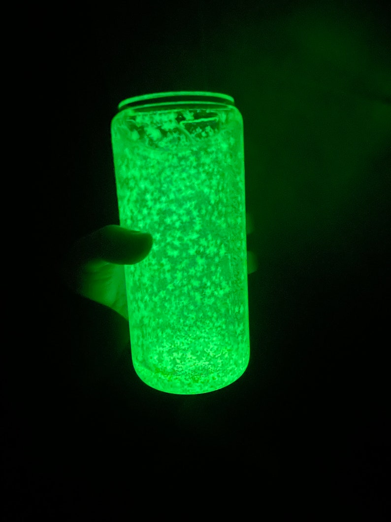 May include: A clear glass tumbler with a green glow and white glitter inside. The tumbler is lit from within, creating a bright green light.