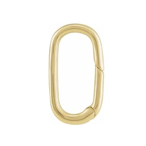 May include: A gold-colored oval-shaped clasp. The clasp is a single piece with a hinged opening on one side. The metal has a smooth, polished finish, reflecting light. The clasp is designed to connect two items.