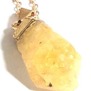 K&ouml;nnte beinhalten: Eine goldene Kettenkette mit einem gelben Kristallanh&auml;nger. Der Kristall ist facettiert und hat ein raues, nat&uuml;rliches Aussehen.