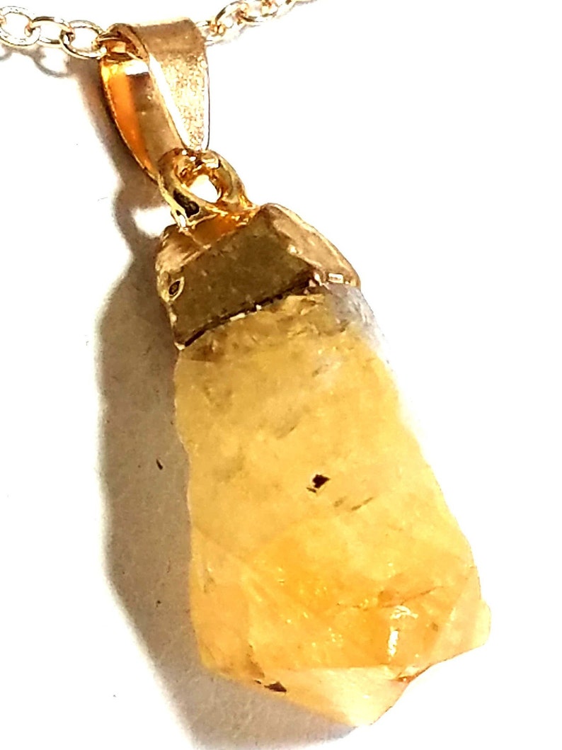 K&ouml;nnte beinhalten: Eine goldene Kettenkette mit einem rohen, gelben Citrin-Kristall-Anh&auml;nger.