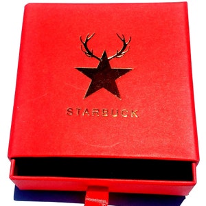K&ouml;nnte beinhalten: Rote Box mit einem goldenen Stern und Geweih, und dem Wort "STARBUCK" auf der Vorderseite. Die Box hat eine Schublade, die ge&ouml;ffnet ist.