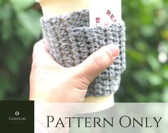 May include: A gray crocheted coffee cup sleeve with a pocket, holding a disposable coffee cup with a white lid. The text "PATTERN ONLY" is at the bottom of the image. The sleeve is handmade and appears to be made of a soft yarn.