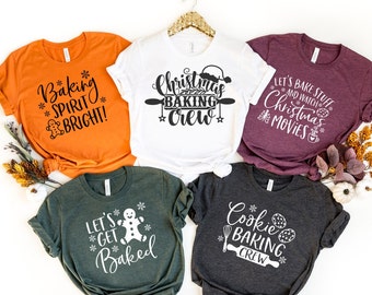 May include: Five short-sleeved t-shirts in various colors, each with a white graphic. The shirts feature holiday-themed baking phrases like "Baking Spirit Bright!" and "Christmas Baking Crew." The shirts are made of a soft material.