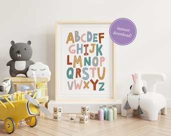 May include: A colorful alphabet poster with a white background and brown frame. The letters are in different colors and have a variety of patterns. The poster is hanging on a white wall in a room with a wooden floor. There are toys and other decorations in the room.