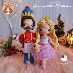 Può includere: Schema di uncinetto per un  soldatino di stagno e una bambola Clara. Il soldatino di stagno indossa un'uniforme rosso e oro con un cappello blu. Clara indossa un vestito rosa con un corpetto bianco e capelli biondi. Lo schema è in inglese.