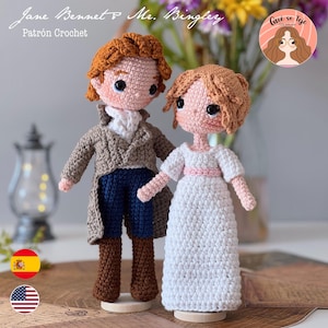 Puede incluir: Dos muñecos de ganchillo, Jane Bennet y Mr. Bingley, están uno al lado del otro. Jane lleva un vestido blanco con una faja rosa. Mr. Bingley viste un abrigo marrón, pantalones azules y botas marrones. El texto "Jane Bennet & Mr. Bingley" está en la parte superior.