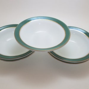 May include: Set of four white bowls with a green and gold rim. The bowls are stacked on top of each other.