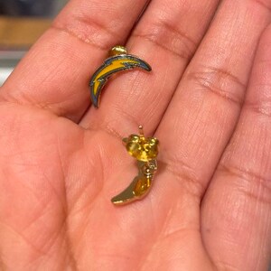 May include: A pair of gold earrings with a lightning bolt design. The earrings are yellow and blue.