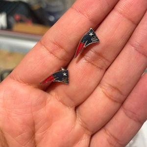 May include: A pair of silver earrings with a red, white, and blue American flag design.