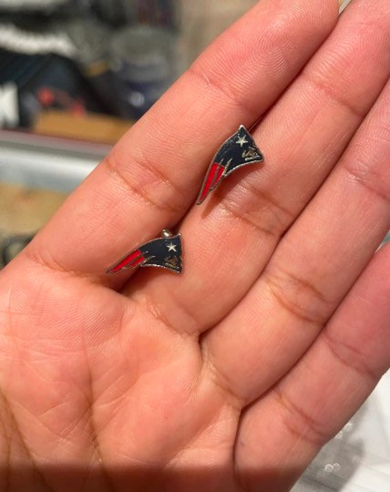 May include: A pair of silver earrings with a red, white, and blue American flag design.