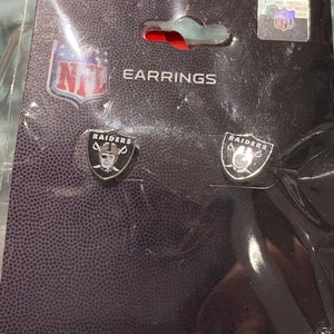 May include: A pair of silver Raiders earrings with the team logo and a player's face on each earring. The earrings are packaged on a black background with the NFL logo and the word "EARRINGS".