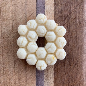 May include: A white cookie shaped like a honeycomb with a hole in the center. The cookie is on a wooden surface.