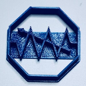 May include: A blue plastic cookie cutter shaped like an octagon with a wavy line design inside.