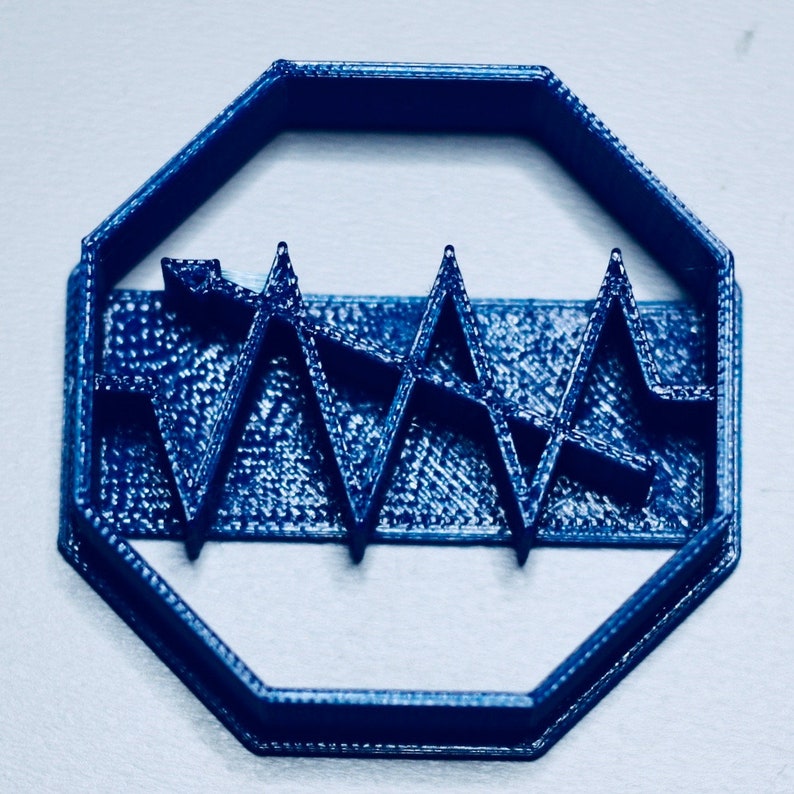 May include: A blue plastic cookie cutter shaped like an octagon with a wavy line design inside.