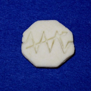 May include: A white cookie with a zig-zag pattern pressed into the surface. The cookie is on a blue background.