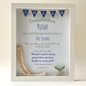 May include: A white frame with a blue and green banner that says "AMEEN" and "Congratulations Yusuf". The frame also includes a wooden prayer beads, a small green book, and a quote in Arabic and English that says "The most superior among you are those who learn the Qur'an and teach it".