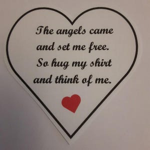 May include: A white heart-shaped card with black text that reads "The angels came and set me free. So hug my shirt and think of me." A small red heart is at the bottom of the card.