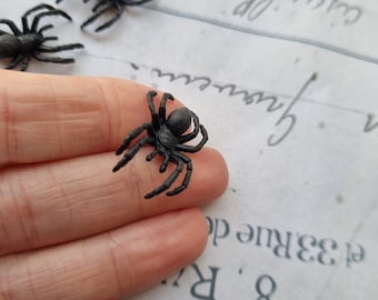 Puede incluir: Un juguete de araña de plástico negro con ocho patas. La araña está siendo sostenida en la mano de una persona.