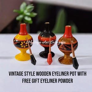 May include: Three vintage-style wooden eyeliner pots with black, brown, and yellow paint. Each pot has a red lid and comes with a wooden applicator. The text "Mystique Art Enterprise" is visible in the image.