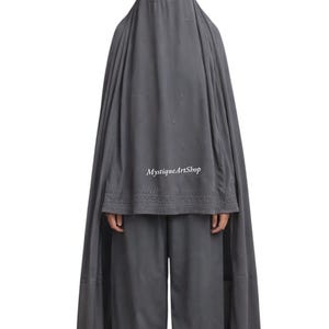 Può includere: Un burqa grigio, una copertura integrale indossata da alcune donne musulmane. L'indumento comprende un copricapo con uno schermo a rete per gli occhi, un lungo mantello e pantaloni abbinati. Il testo "MystiqueArtShop" è visibile.