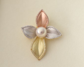 May include: A gold, silver, and rose gold flower pendant with a pearl in the center.