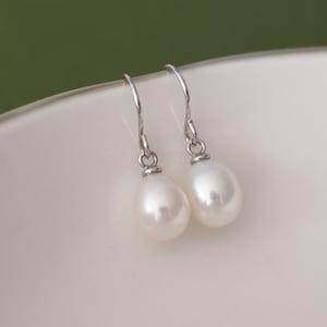 May include: A pair of silver dangle earrings with white pearl drops.